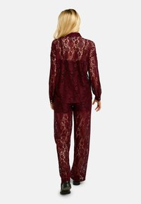 Bordový čipkovaný dvojdielny komplet s dlhými rukávmi, kvetinovým vzorom a voľnými nohavicami s priesvitným, textúrovaným povrchom.