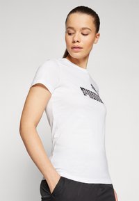 White cotton t-shirt with a crew neckline and short sleeves, featuring a black graphic logo across the chest, fitted design.