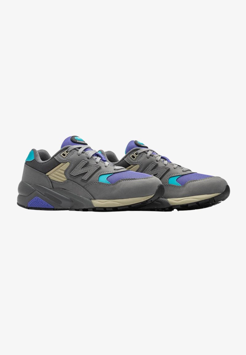 Baskets de sport grises avec des accents violets et turquoises, featuring un mélange de matériaux en maille et en daim, semelles en caoutchouc plates et œillets renforcés.