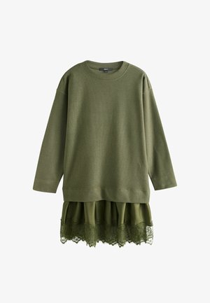 Roheline pika varrukaga kootud kampsun kihilise satiinse seelikusäärisega, millel on pitsist ääris, rippumas valgel taustal.