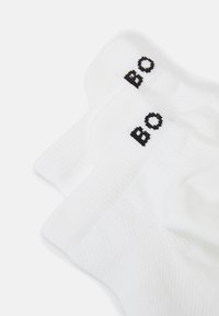 Witte katoenen sokken met ribbelstructuur, voorzien van een zwart geborduurd "BO" op de boorden. Eenvoudige, atletische stijl die geschikt is voor dagelijks gebruik.