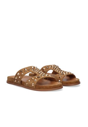 Sandalias planas tipo slide de gamuza marrón con tachuelas piramidales doradas que cubren las correas cruzadas y suelas de goma planas, mostradas sobre un fondo blanco.
