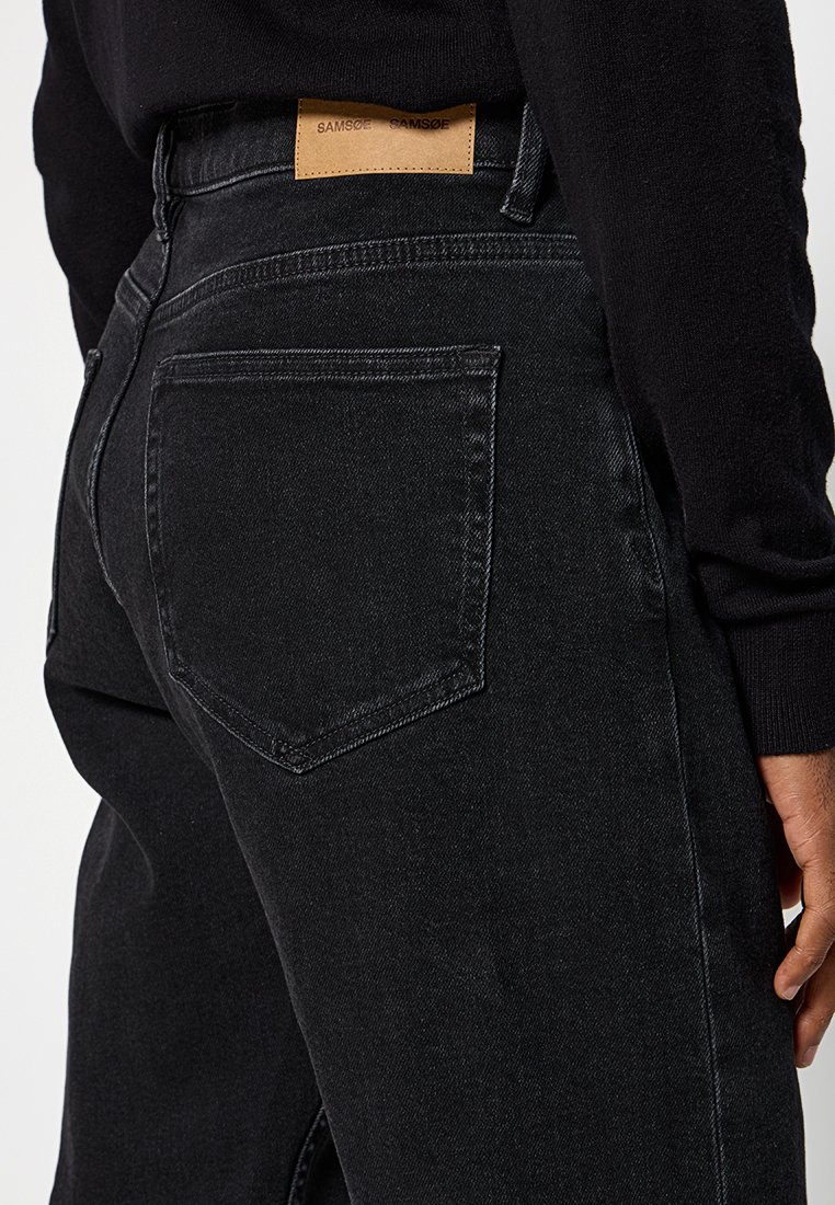 Czarne dżinsy denimowe o prostym kroju, z skórzaną naszywką w pasie oraz klasycznymi tylnymi kieszeniami z przeszytymi brzegami.