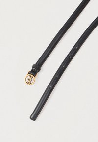 Melnas ādas josta ar šauru siksnu, zeltītu apaļu sprādzi ar divām putniem un vairākām regulēšanas caurumiem uz gaiša fona.