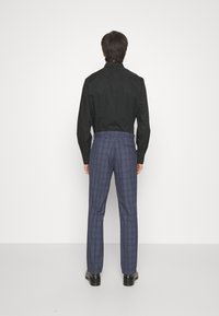 Black button-up shirt, navy checkered trousers, straight cut, smooth fabric, and black shoes. Simple design with contrasting patterns.
