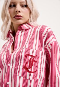 Rdeča in roza srajca z gumbi, z levim žepom na prsih in izvezeno črko "F". Mehka bombažna tkanina.