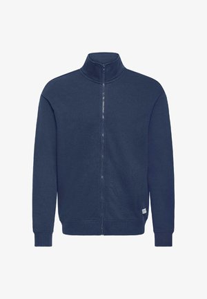 Marineblå genser med glidelås, høy krage, ribbestrikkede mansjetter og nederkant, laget av et mykt materiale. Har en liten logopatch nederst.