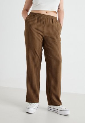 Brown striped trousers with an elastic waistband and side pockets, made from a soft fabric. Worn with white sneakers.