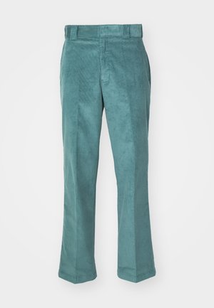 Pantaloni din catifea la culoarea teal, cu un design drept, având o textură netedă, bucle pentru curea și buzunare laterale. Fără modele vizibile sau accesorii.