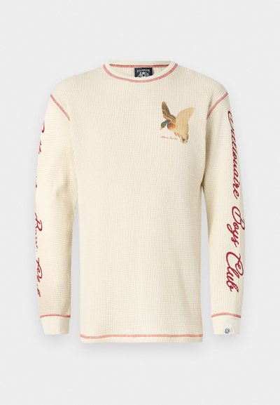 Waffle-knit cream long-sleeve shirt with red accent stitching. Features bird graphic on chest and "Billionaire Boys Club" text on sleeves.
