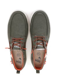 Chaussures en toile vertes avec des accents orange, à bout rond et semelle en caoutchouc blanche. Présentent des lacets et une languette à l'arrière. Design plat.