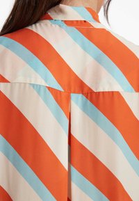 Kurzarmhemd mit diagonalen orange und hellblauen Streifen auf glattem Stoff, mit Kragen und einem Rückenschlitzdetail.