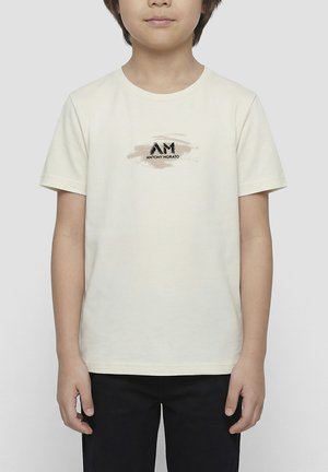 Enfant portant un t-shirt beige à manches courtes avec le logo "AM Antony Morato" imprimé sur la poitrine, associé à un pantalon noir.