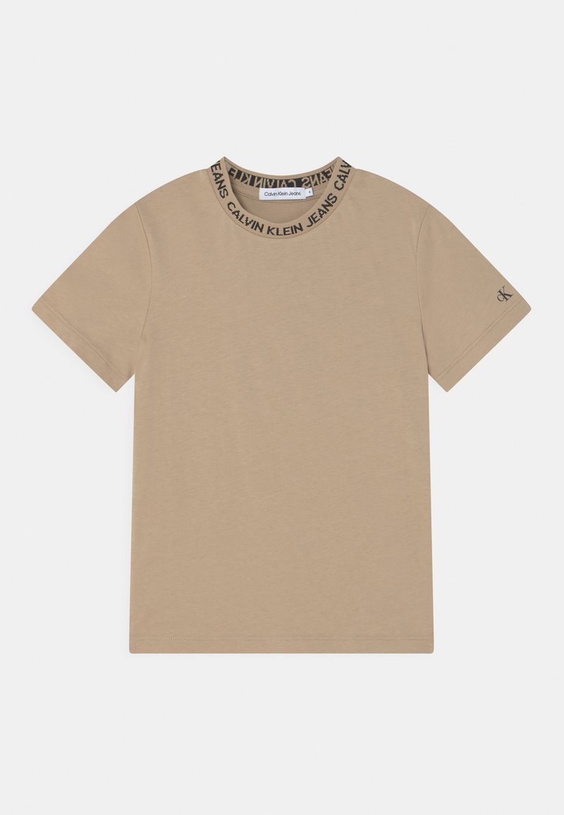 T-shirt beige à manches courtes avec col rond, arborant une bande de logo noire. Tissu en coton doux et lisse avec une finition propre sur les manches et l'ourlet.