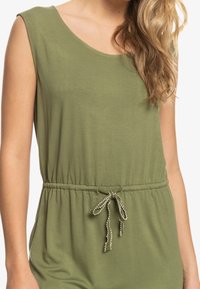 Olivově zelený overal bez rukávů s kulatým výstřihem a elastickým pasem, se zdobnou šňůrkou s kontrastními detaily.