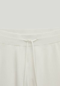 Pantalon en tissu blanc avec une taille élastique côtelée et un cordon à nouer à l'avant au centre.