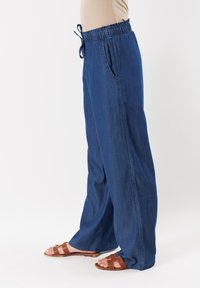 Pantaloni in denim a gamba larga di un blu intenso, con vita elastica e coulisse regolabile. Presentano tasche laterali e una vestibilità rilassata.