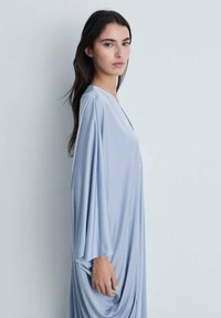 Light blue draped dress with batwing sleeves, smooth texture, relaxed fit, and gathered details at the side. Elegant and minimalist design.
