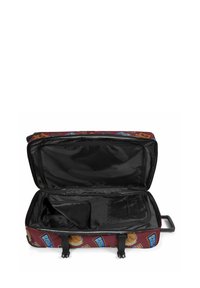 Bolso de viaje rojo con forma plana y ancha y varios parches coloridos. El interior presenta un forro negro con un compartimento con cremallera y organizador.