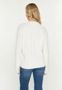Pullover color crema a maglia cable con fondo a costine, caratterizzato da un motivo a diamante testurizzato e una vestibilità leggermente ampia.