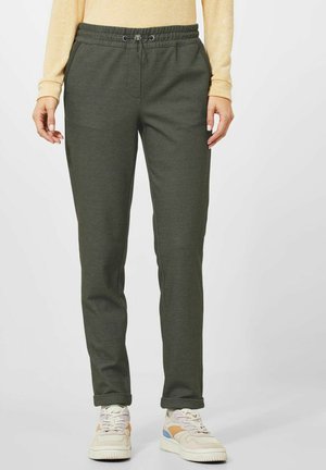 Green patterned pants with an elastic waistband and adjustable drawstrings, paired with light-colored sneakers. Straight leg design.