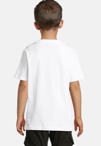 Balta medvilninė marškinėliai su trumpomis rankovėmis, apvaliu iškirpimu ir tiesiu apvadu, rodomi iš nugaros, be matomų grafikos ar raštų.