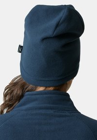 Beanie in pile navy con una texture morbida, progettato per una vestibilità aderente. Presenta un piccolo etichetta con il marchio posizionata di lato.