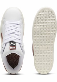 Sneaker bianca con suola in gomma testurizzata e linguetta imbottita. Presenta un accento rosso, una toppa con il logo e lacci intrecciati. Parte superiore in sintetico liscio.