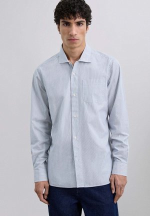 Camisa de botones azul claro con rayas blancas verticales, un bolsillo en el pecho y mangas largas, hecha de una suave mezcla de algodón.