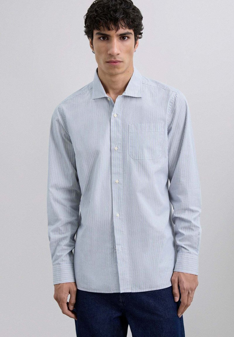 Camisa de botones azul claro con rayas blancas verticales, un bolsillo en el pecho y mangas largas, hecha de una suave mezcla de algodón.