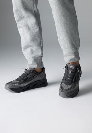 Black and gray athletic shoes featuring a mesh upper, textured pattern, and rounded sole with ventilation ports. Lace-up design.