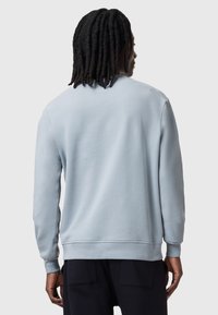 Maglione azzurro chiaro con maniche lunghe, texture liscia, polsini e orlo a costine, e un design classico a girocollo.