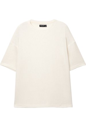 Fehér, bordázott kötött póló kerek nyakkivágással és rövid ujjakkal. Puha tapintású, laza szabású, látható logók vagy minták nélkül.