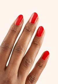 Esmalte de uñas rojo en cinco dedos con un acabado liso y brillante. El tono de piel es marrón cálido con texturas y detalles visibles en los dedos.