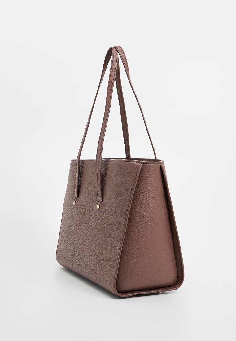 Braune, strukturiert Leder Tote-Bag mit langen Schulterriemen und minimaler goldener Hardware, seitlich auf weißem Hintergrund abgebildet.