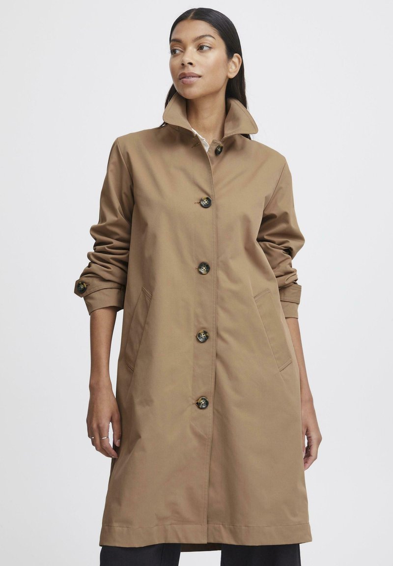 Cappotto marrone fino al ginocchio con colletto alto, cinque bottoni e due tasche laterali, realizzato in tessuto liscio con una leggera lucentezza.