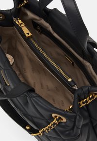 Czarna pikowana skórzana torebka z elementami w kolorze złotym i beżowym wnętrzem z kieszenią na zamek oraz wzorem logo.