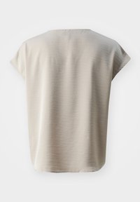Haut court beige clair à manches courtes, fabriqué en tissu doux. Il présente un col rond et une coupe décontractée avec une texture lisse et sans motifs visibles.