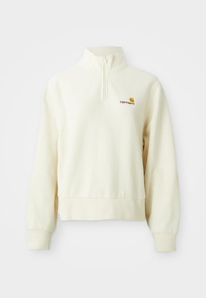 Cremefarvet pullover med høj krave og halv lynlås. Har ribbede manchetter og et logo på venstre brystområde. Blød, glat tekstur.