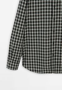 Schwarz-weiß kariertes Langarmhemd mit geknöpftem Manschettenverschluss und schwarzen Knöpfen vorne, dargestellt vor weißem Hintergrund.