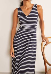 Marinblå och vitrandig klänning med V-ringning, utan ärmar, elastisk midja och en svängd nederdel. Lätt, elastisk tyg.