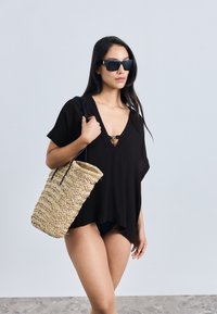 Crni prekidač s V-izrezom, kratkim rukavima i detaljem prednje kopče, upareni s pletenom slamnom torbom s crnim drškama.