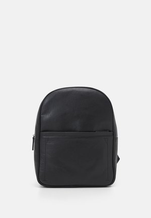 Czarny skórzany plecak z przednią kieszenią na zamek na jednolitym jasnoszarym tle.