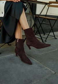 Dark burgundy suede ankle boots with pointed toes and short block heels, featuring a side zipper and smooth texture.