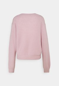Pull côtelé rose clair avec une coupe décontractée, un col rond et des manches longues. L'ourlet est légèrement raccourci, mettant en valeur une texture douce.