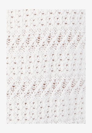 Tessuto lavorato a maglia bianco con un motivo strutturato che presenta linee diagonali e piccoli puntini marroni, mostrando un'abilità artigianale intricata.