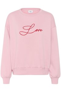 Roza pulover s dolgimi rokavi, z ribanim robom in manšetami; na sprednji strani se nahaja rdeče vezen napis "Ljubezen" v kurzivnem fontu.