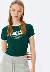 Camiseta de algodón verde con cuello de ringer blanco, con la frase "Los Angeles California College League desde 1992" en color blanco.