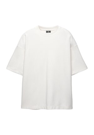 Tricou alb cu mânecă scurtă, cu gât rotund, având o croială lejeră, un material texturat și detalii de tiv cusute. Fără grafică vizibilă.