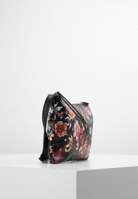 Černá květinová kabelka s embosovanými květinami v různých barvách, kovovými cvočky a zipovým uzávěrem. Měkká, texturovaná tkanina.